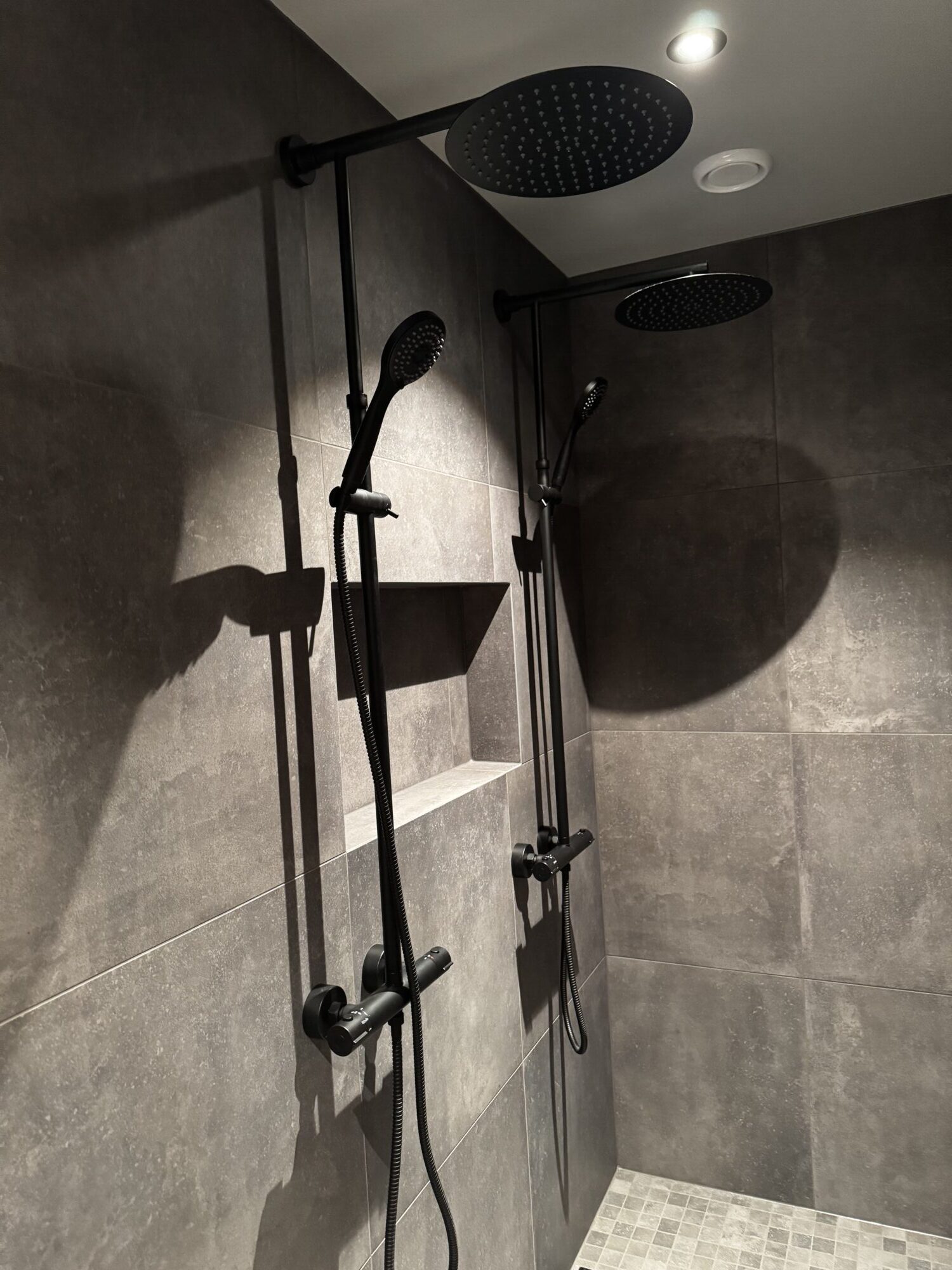 En av dusjsonene med nisje innbygd i veggen mellom de to armaturene